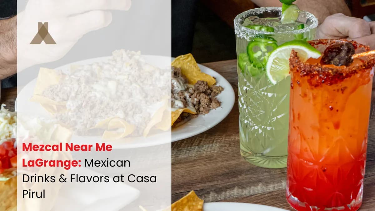 A jalapeno-topped green cocktail and a chamoy-rimmed red one on a wooden table, beside plates of nachos